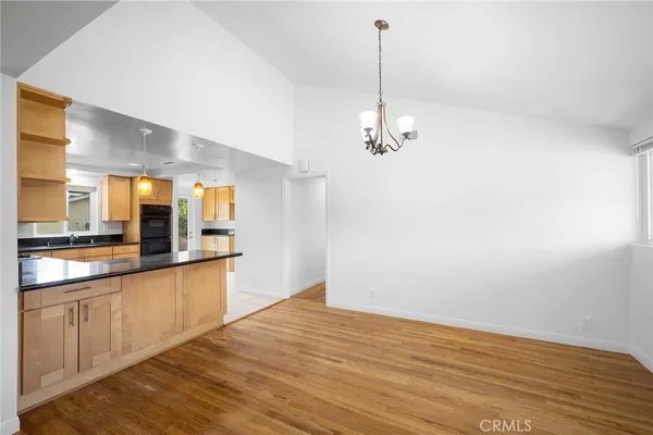 a view of a kitchen with stainless steel appliances granite countertop a sink and cabinets with wooden floor