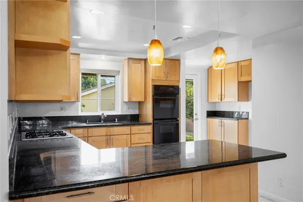 a kitchen with stainless steel appliances granite countertop a sink a stove and a refrigerator