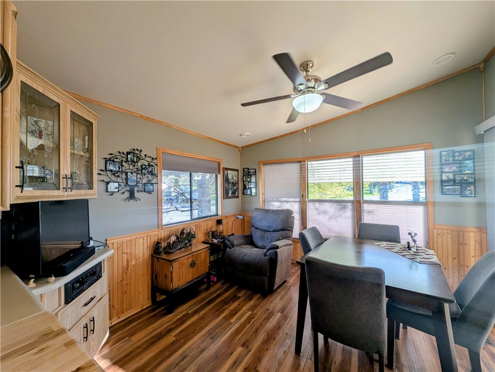 2000 Ramar Road, Unit 89 Bullhead City, AZ 86442 - Photo 16 of 26 Dining room featuring a wainscoted wall, wood walls, lofted ceiling, crown molding, and dark wood-type flooring