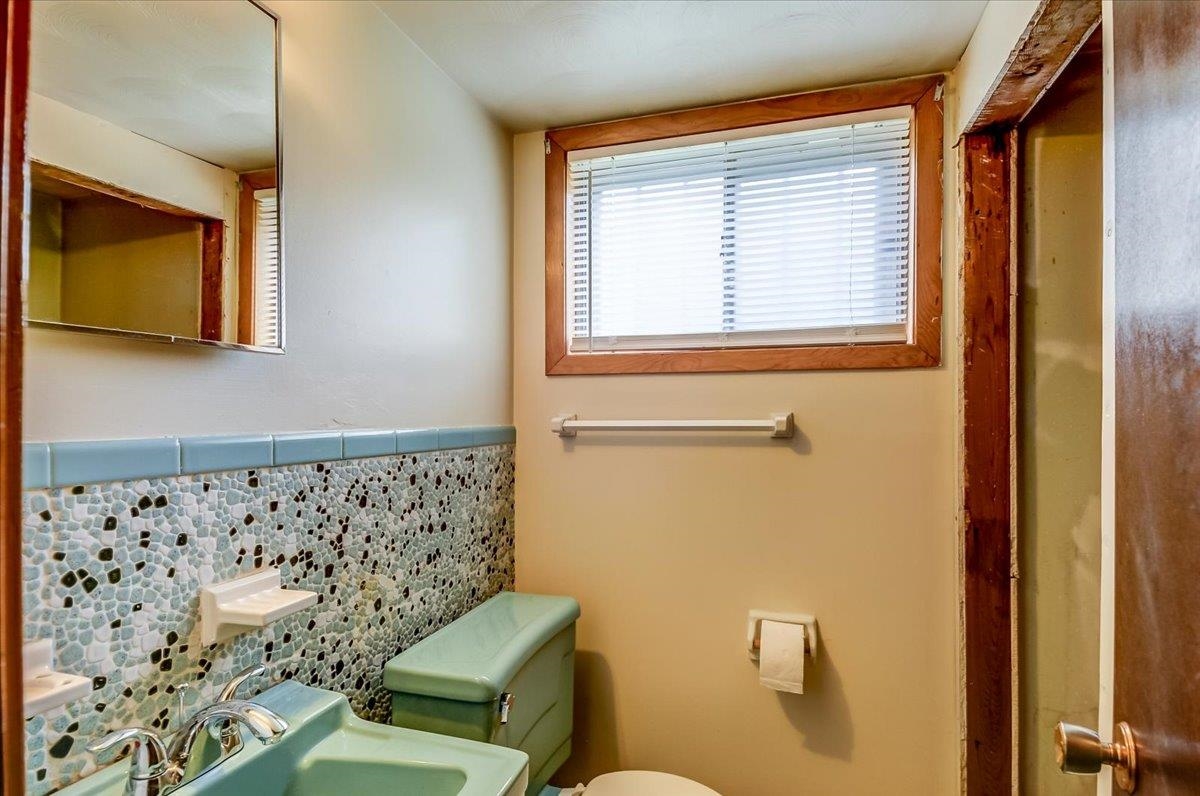 2569 Rozelle Street Memphis, TN 38114 - Photo 24 of 30 Bathroom featuring green fixtures, mosaic tile wainscoting, and a mirrored medicine cabinet
