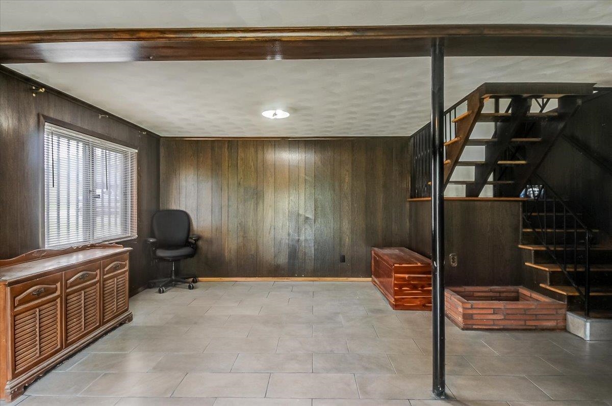 2569 Rozelle Street Memphis, TN 38114 - Photo 9 of 30 Finished lower level featuring panel walls, tile flooring, a window with blinds, and an open staircase with a metal railing