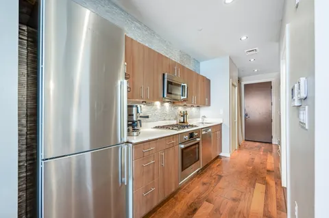 a kitchen with stainless steel appliances granite countertop a refrigerator a stove top oven a sink and dishwasher
