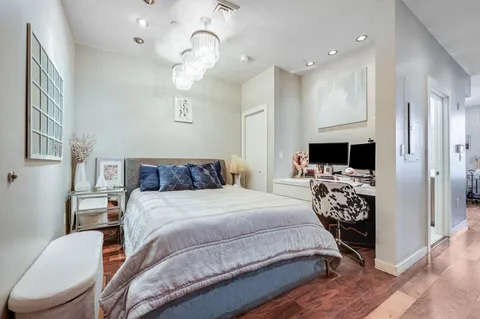a bedroom with a bed a mirror on dresser and a chandelier