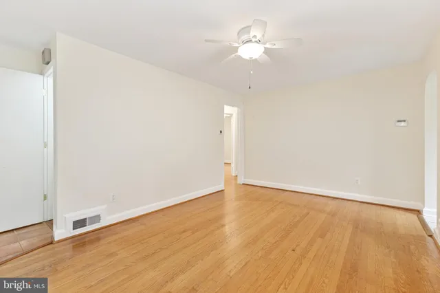 an empty room with wooden floor and ceiling fan