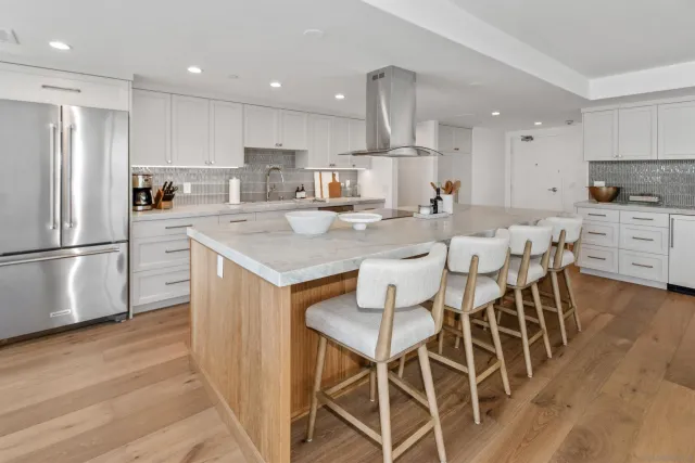 a kitchen with stainless steel appliances a dining table chairs refrigerator sink and cabinets