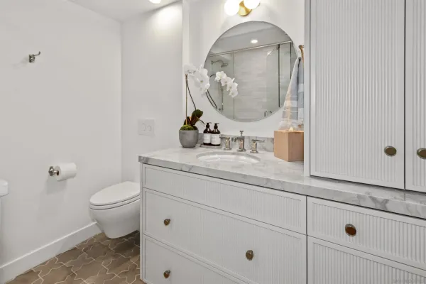 a bathroom with a granite countertop toilet sink and mirror