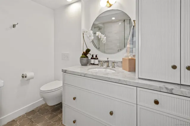 a bathroom with a granite countertop toilet sink and mirror