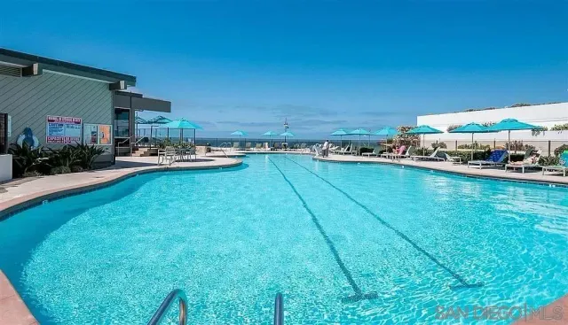 a view of a lake with lawn chairs and large trees