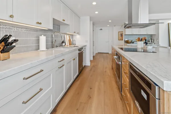 a large kitchen with stainless steel appliances lots of counter space and wooden floor