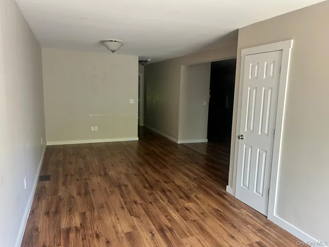 a view of a hallway with wooden floor and a bathroom