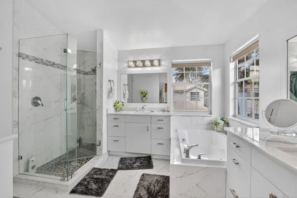 a bathroom with a double vanity sink a mirror a bathtub and shower