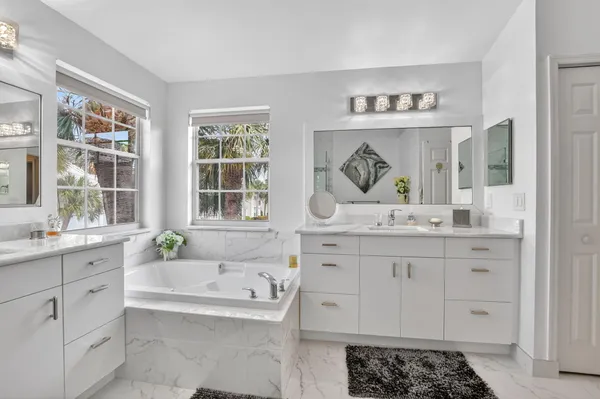 a bathroom with a granite countertop tub sink a mirror and next to a window