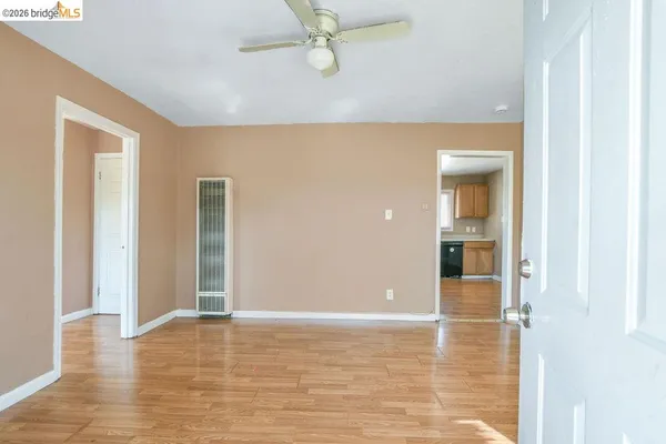 a view of an empty room with a window and wooden floor