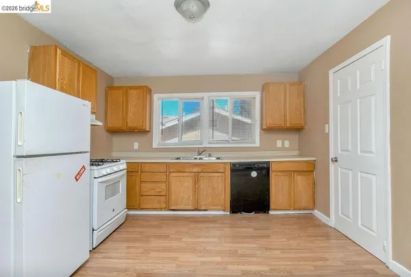 a kitchen with stainless steel appliances granite countertop a stove a sink dishwasher a refrigerator and white cabinets with wooden floor
