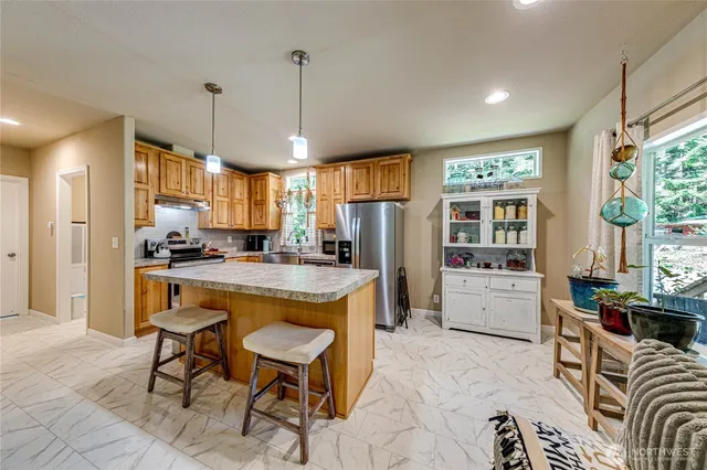 a large kitchen with kitchen island a large counter top space a sink stainless steel appliances and cabinets