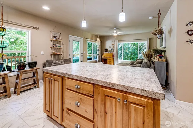 a kitchen with kitchen island granite countertop a stove a sink a counter space and living room view
