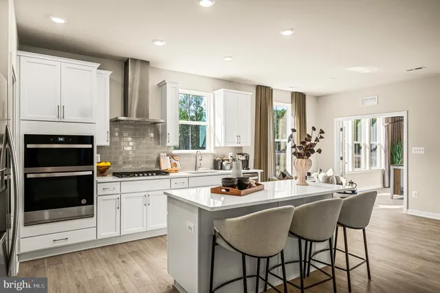 a kitchen with stainless steel appliances kitchen island granite countertop a stove a sink dishwasher and cabinets with wooden floor