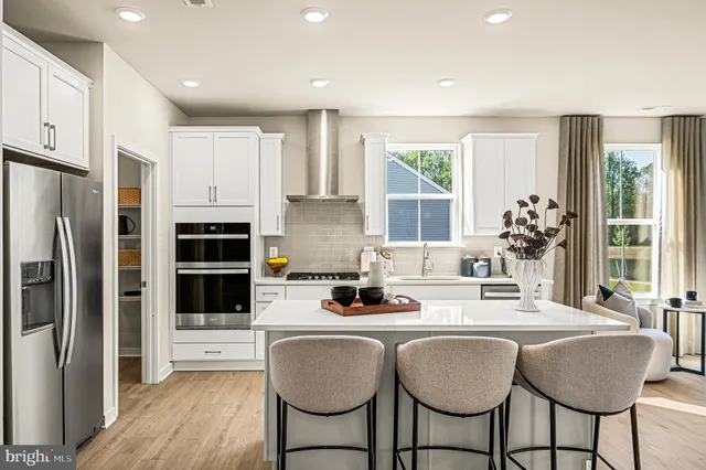 a kitchen with stainless steel appliances granite countertop a dining table chairs refrigerator and sink