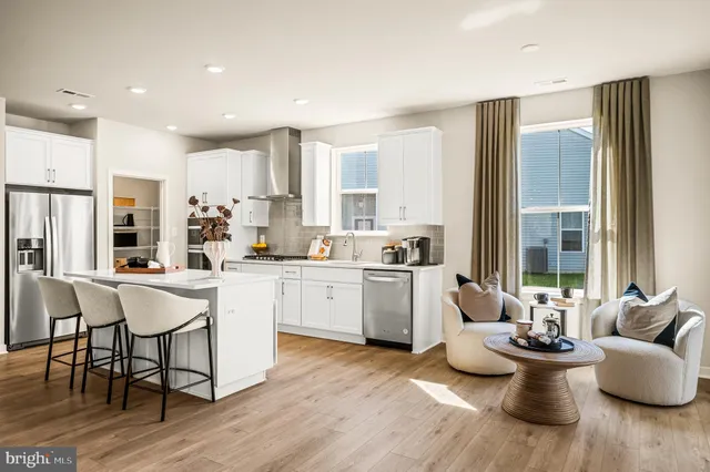 a kitchen with a dining table chairs stainless steel appliances and windows