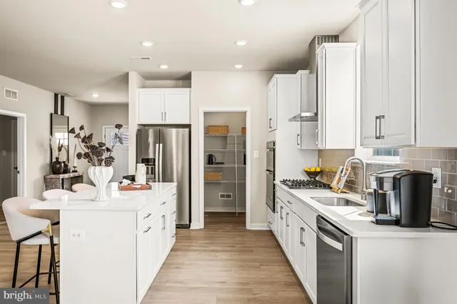 a kitchen with stainless steel appliances a sink stove refrigerator and cabinets