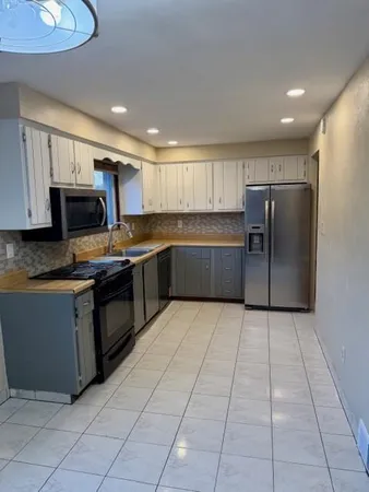 a kitchen with stainless steel appliances granite countertop a refrigerator and a stove top oven