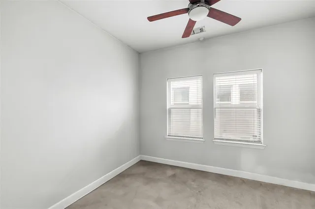 an empty room with a window and a fan
