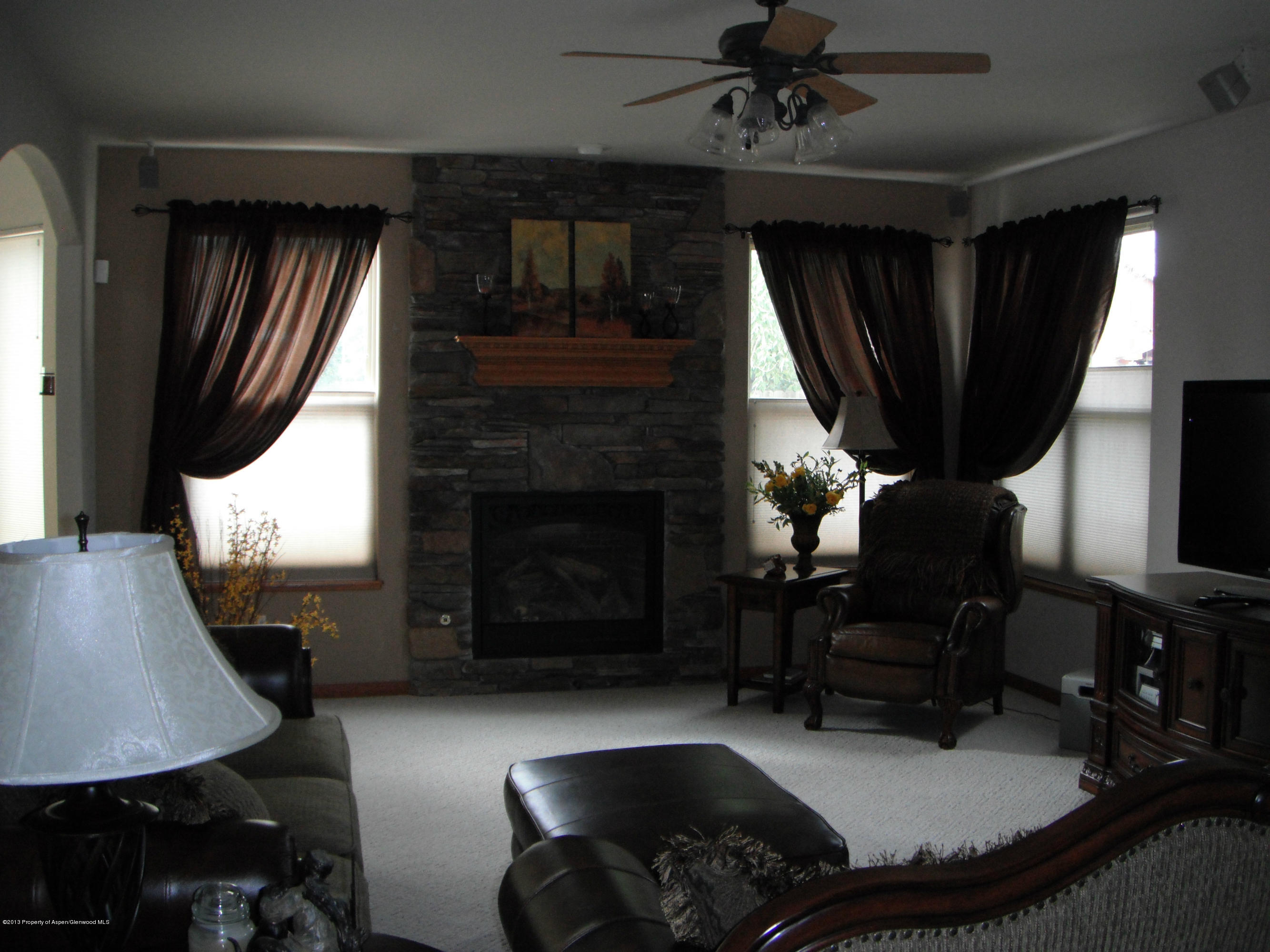 1298 Fir Avenue Rifle, CO 81650 - Photo 6 of 27 a living room with furniture a fireplace a flat screen tv and a large window
