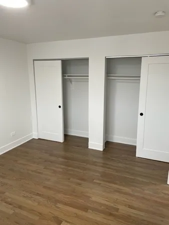 a view of an empty room with wooden floor and closet