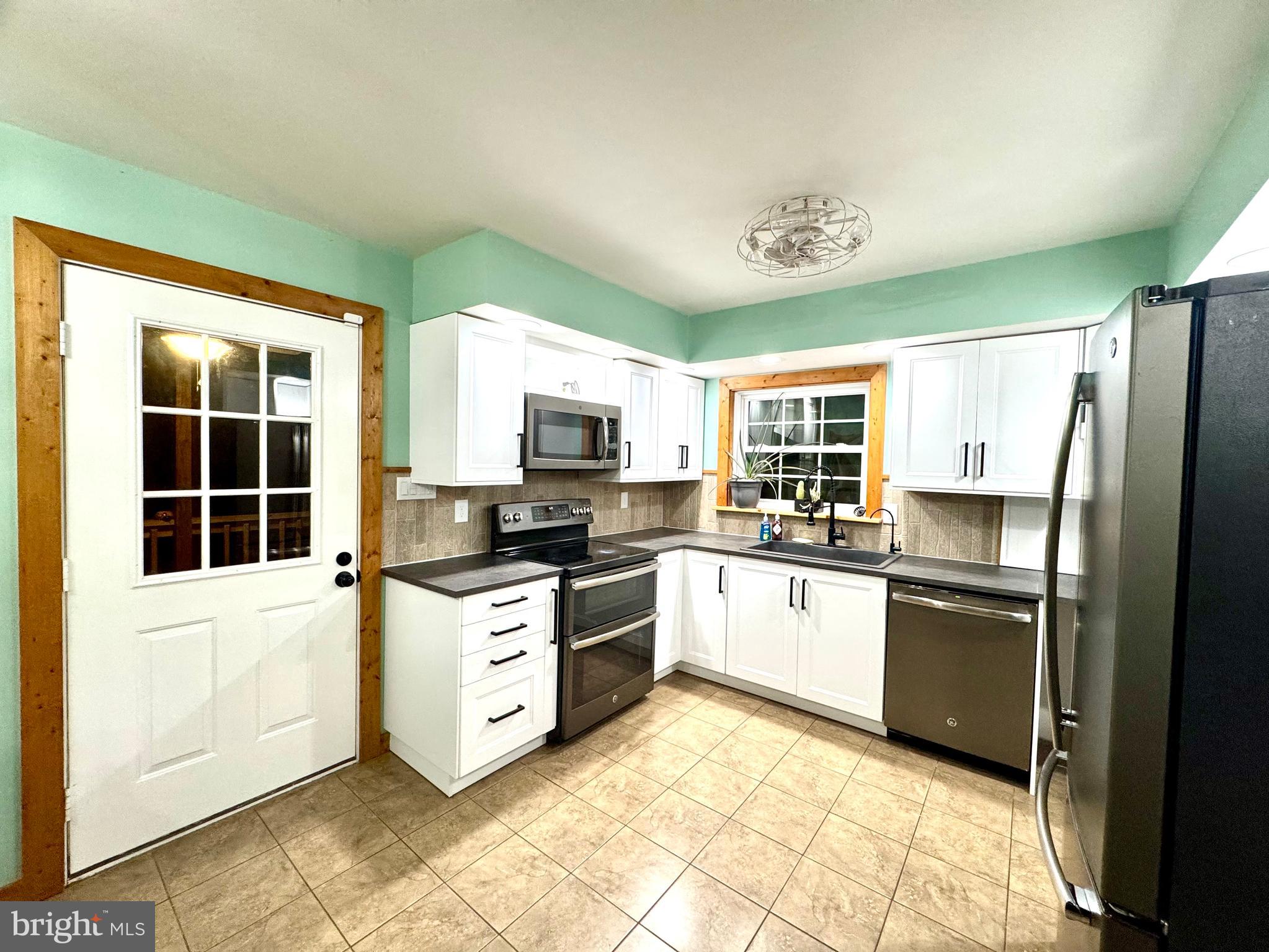 4695 Shelltown Road Marion Station, MD 21838 - Photo 15 of 31 a kitchen with stainless steel appliances granite countertop a stove top oven a sink dishwasher a refrigerator and white cabinets with wooden floor