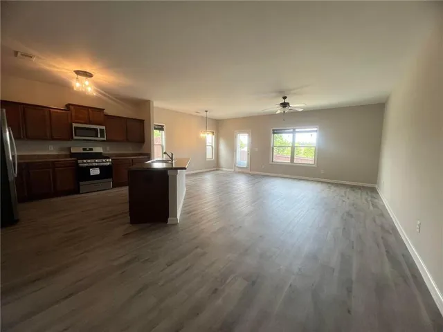 a kitchen with stainless steel appliances granite countertop a refrigerator a stove top oven a sink dishwasher and wooden floor