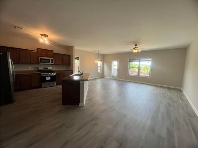 a kitchen with stainless steel appliances granite countertop a stove top oven a refrigerator with wooden floors and cabinets