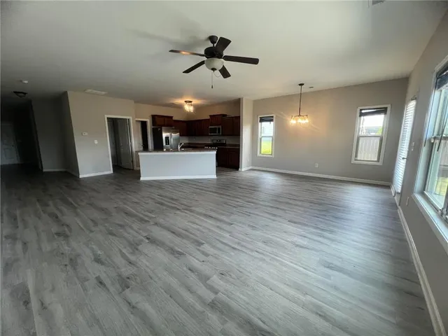 an empty room with wooden floor ceiling fan and window