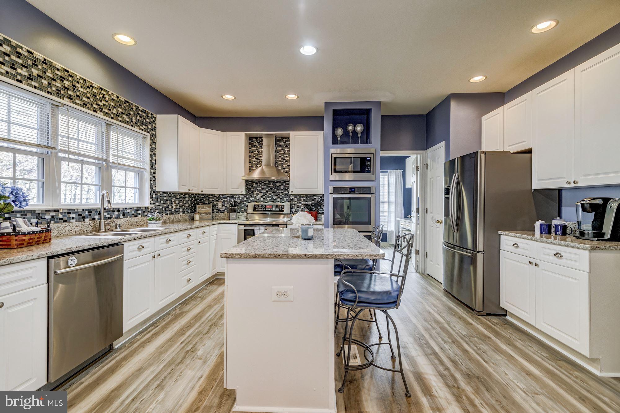 6092 Deer Ridge Trail Springfield, VA 22150 - Photo 7 of 30 a kitchen with stainless steel appliances kitchen island granite countertop a refrigerator a stove a sink and white cabinets with wooden floor