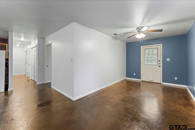 an empty room with wooden floor and a ceiling fan