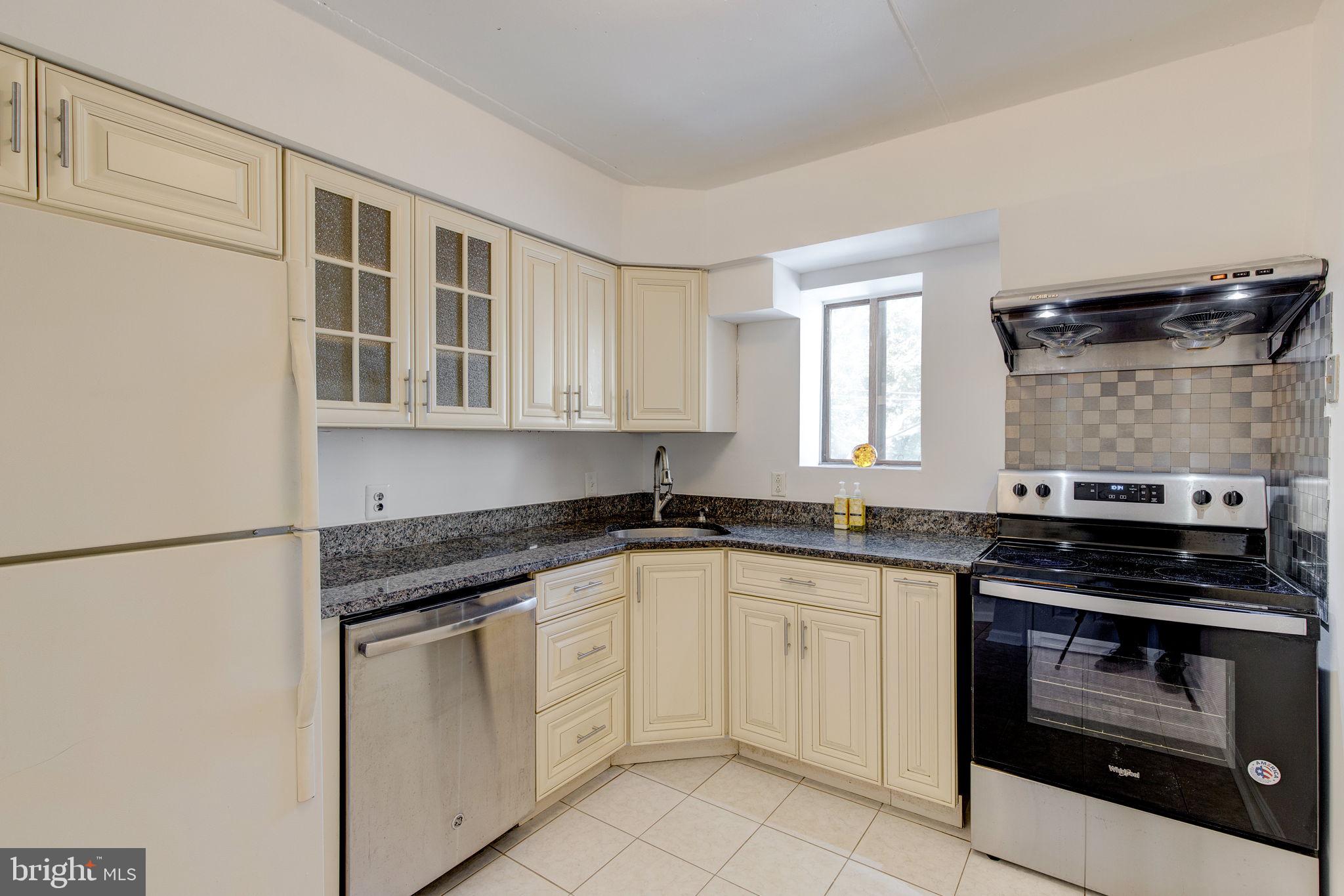 100 Rutgers Avenue, Unit 8 Swarthmore, PA 19081 - Photo 16 of 29 a white kitchen with granite countertop a stove top oven microwave and cabinets
