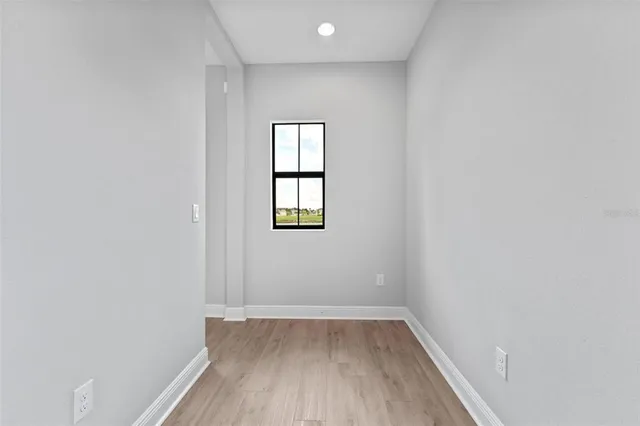 a view of an empty room with wooden floor and a window