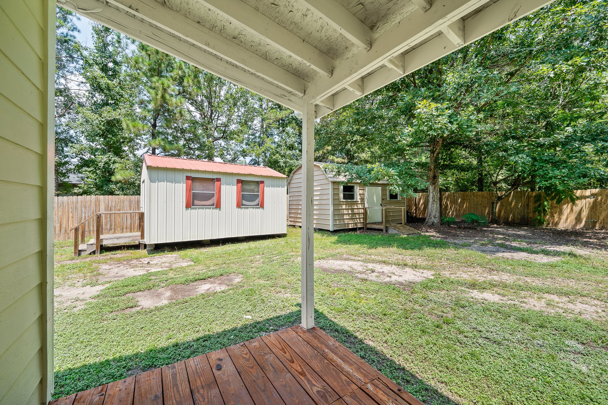 61 Hicks Loop West Cleveland, TX 77328 - Photo 34 of 38 Spacious backyard with covered patio and two storage sheds, surrounded by mature trees for added privacy.