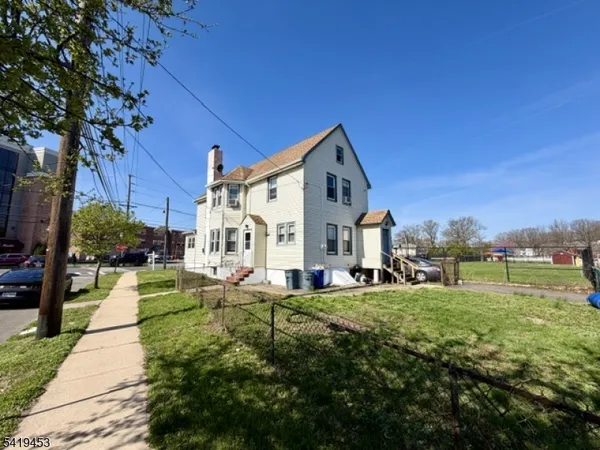 a view of a house with a big yard and large trees