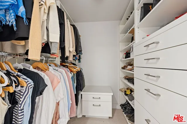 a view of walk in closet with clothes and shoes