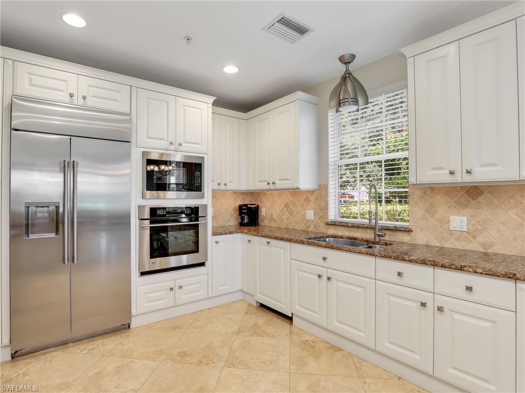 2718 Callista Court, Unit 101 Naples, FL 34114 - Photo 7 of 34 a kitchen with granite countertop white cabinets and stainless steel appliances