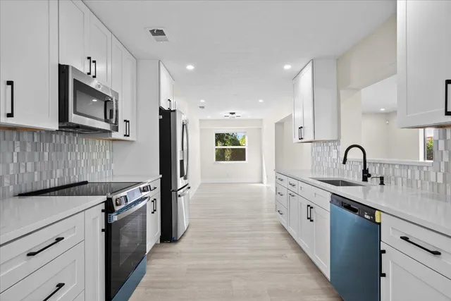 a large white kitchen with wooden floors appliances and cabinets