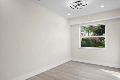 an empty room with wooden floor and natural light
