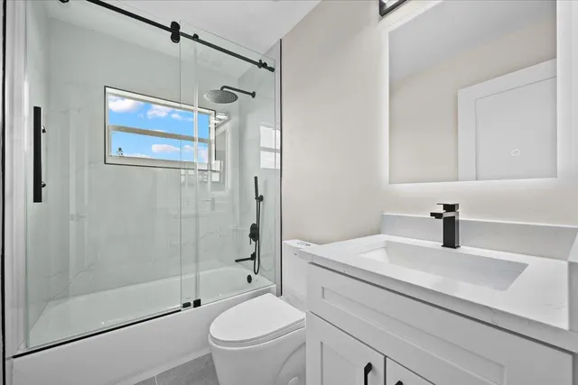 a bathroom with a bathtub shower sink vanity and toilet