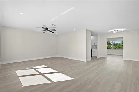 a view of empty room with wooden floor and ceiling fan