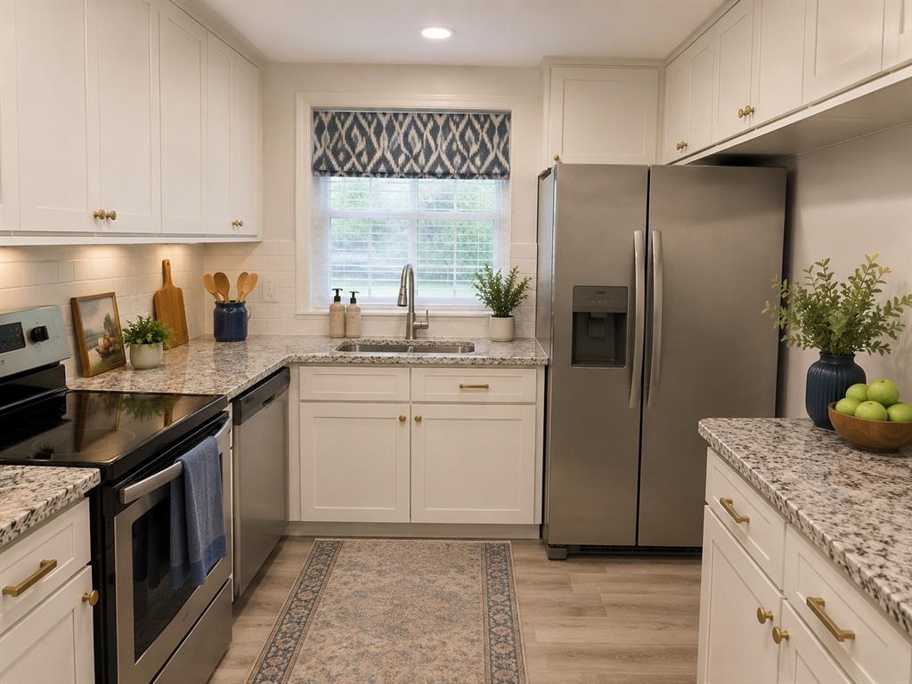 1109 North Howeth Street Gainesville, TX 76240 - Photo 2 of 11 Contemporary kitchen featuring white shaker cabinetry, stainless steel appliances, speckled countertops, and wood-finish flooring