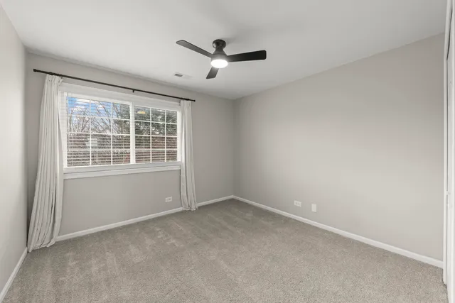 an empty room with window and a ceiling fan