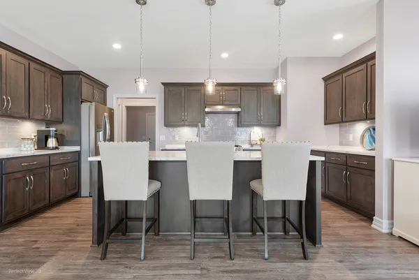 a kitchen with a dining table chairs and wooden floor