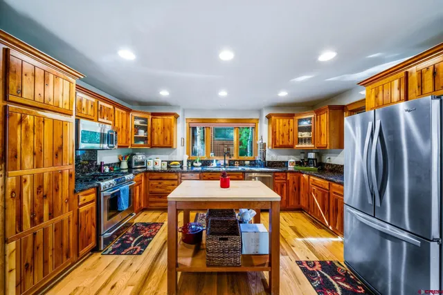 a kitchen with stainless steel appliances granite countertop a stove top oven a sink and a refrigerator