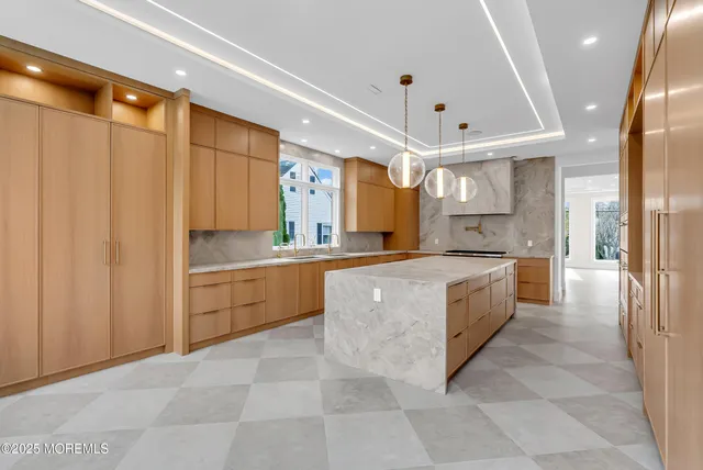 a large kitchen with granite countertop a large counter top and stainless steel appliances
