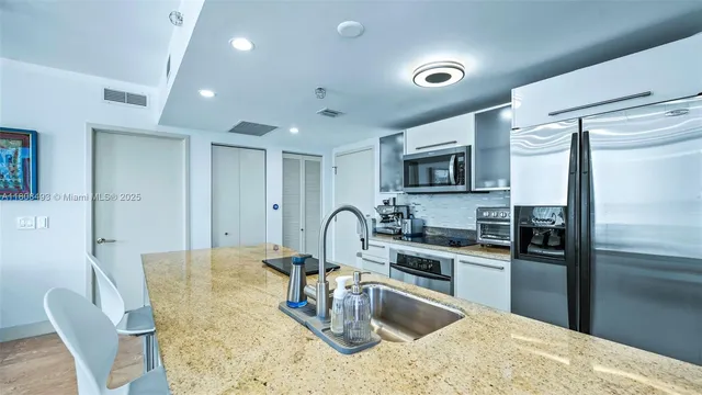a kitchen with granite countertop a refrigerator and a stove top oven